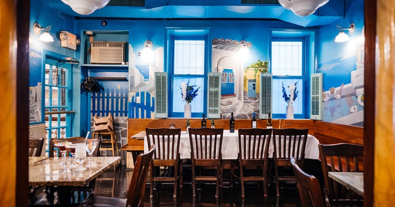Interior, tables and chairs ready for guests, bac door, mural of Santorini