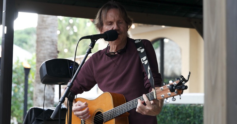 A person playing a guitar and singing into a microphone