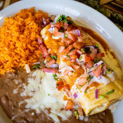 Pork burrito, topped with cheese sauce and pico de gallo, served with rice and beans.