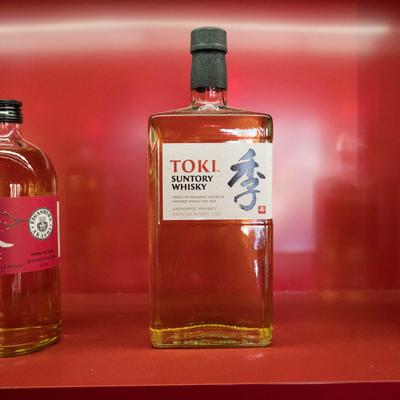 Japanese whisky bottles displayed on a red shelf.