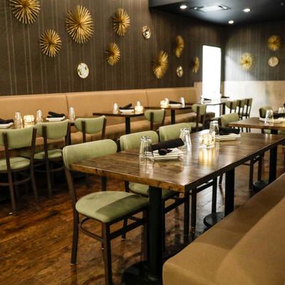 Interior featuring wooden communal tables, upholstered chairs and a decorated wall.