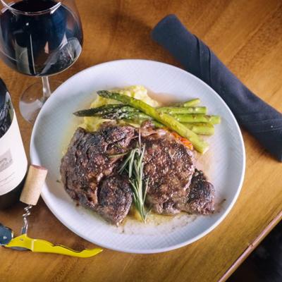 Grilled Ribeye steak served over mashed potatoes, asparagus and carrots.