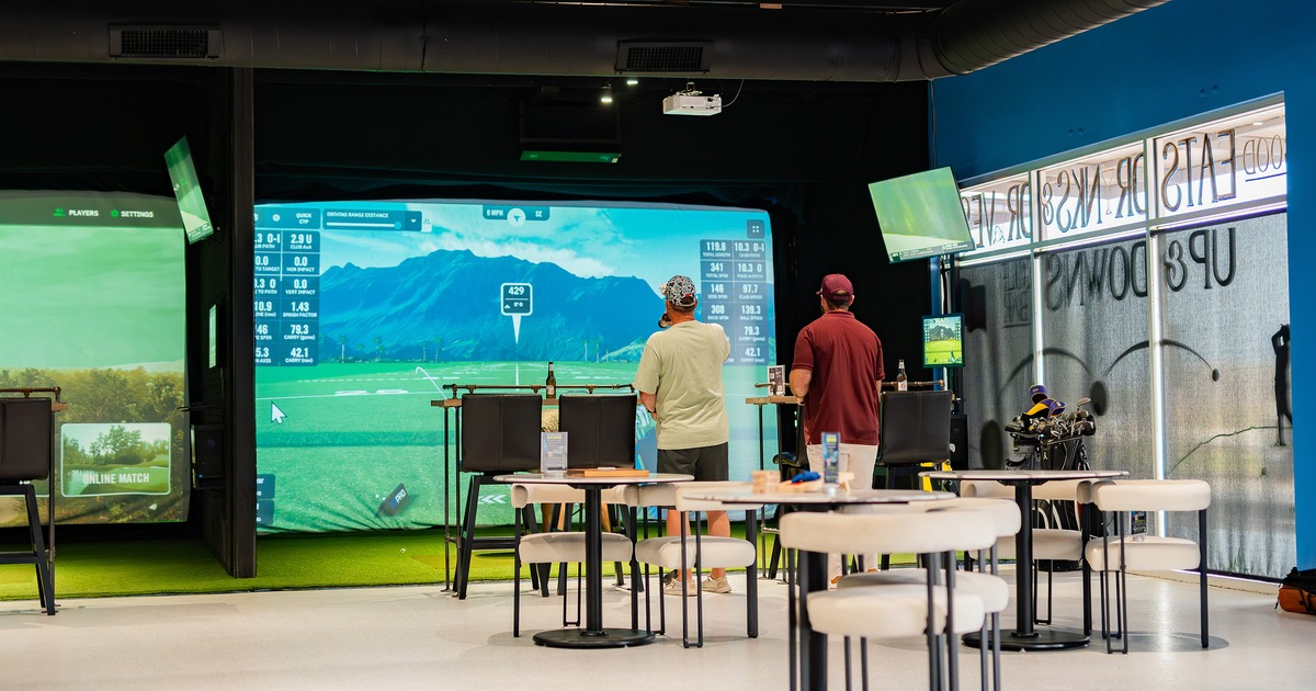 Interior of a modern entertainment space featuring a golf simulator