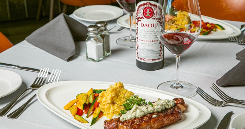 Steak topped with bleu cheese, served with mashed potatoes, vegetables, and red wine