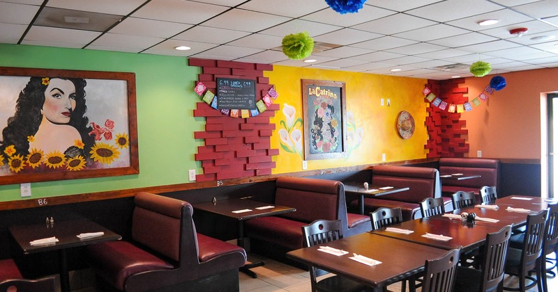 Interior, restaurant booths by a wall decorated with pictures and fiesta decorations