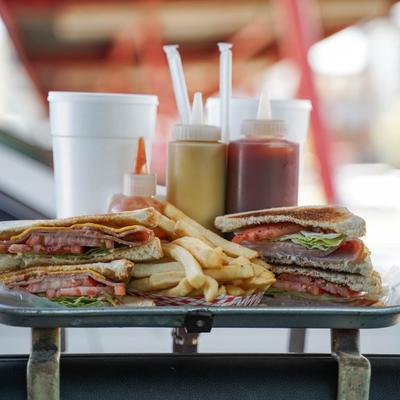ham sandwiches and fries on tray hanging from car window.