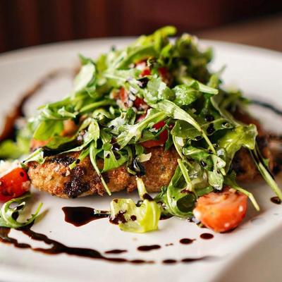 Stuffed Pork Tenderloin topped with a fresh arugula and cherry tomatoes.
