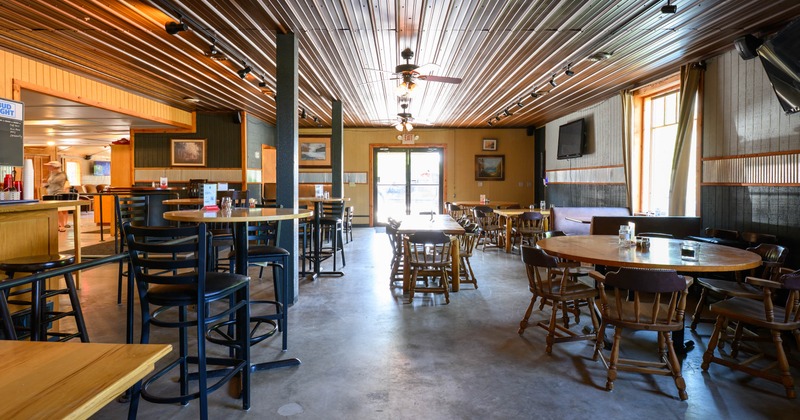 Interior - wooden tables, black chairs, concrete floors, a ceiling of metal panels, a counter area