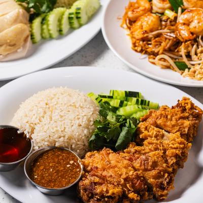 Thai-style crispy fried chicken rice with dipping sauces and cucamber slices.