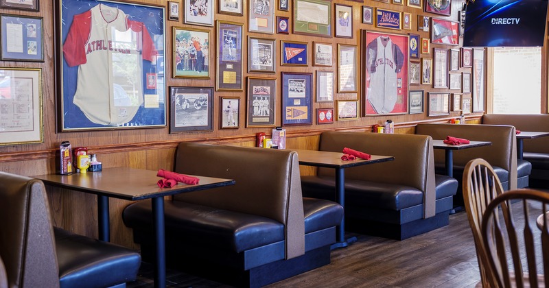 Interior, lined up upholstered dining booths, wall decorated with sports pictures