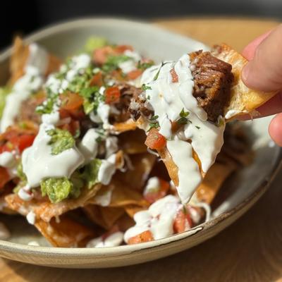 Slow Cooked Beef Barbacoa Nachos with fresh guacamole, sour cream, Pico de gallo on home made tortilla chips.