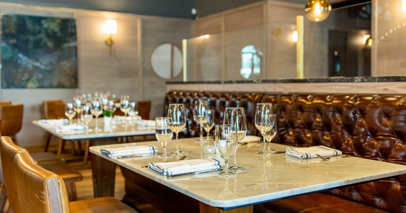 Interior, set dining tables, chairs and button tufted leather booth seating