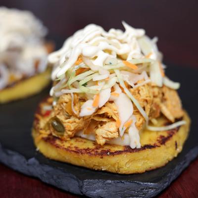 Venezuelan pancake topped with shredded chicken, coleslaw, and sauce.