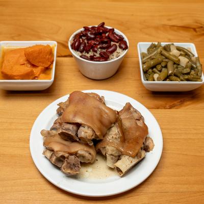 Pigs feet served with sweet potatoes, red beans and rice, and green beans.
