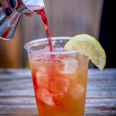 iced green tea with strawberry syrup being added.