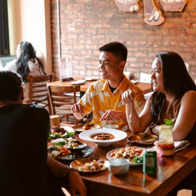 A group of people sitting at a wooden table in a restaurant sharing a mea.