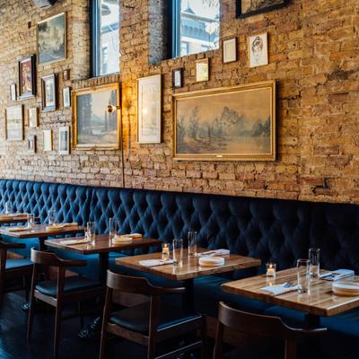 Dinning area with banquette seating, set tables with candles, pictures on the wall