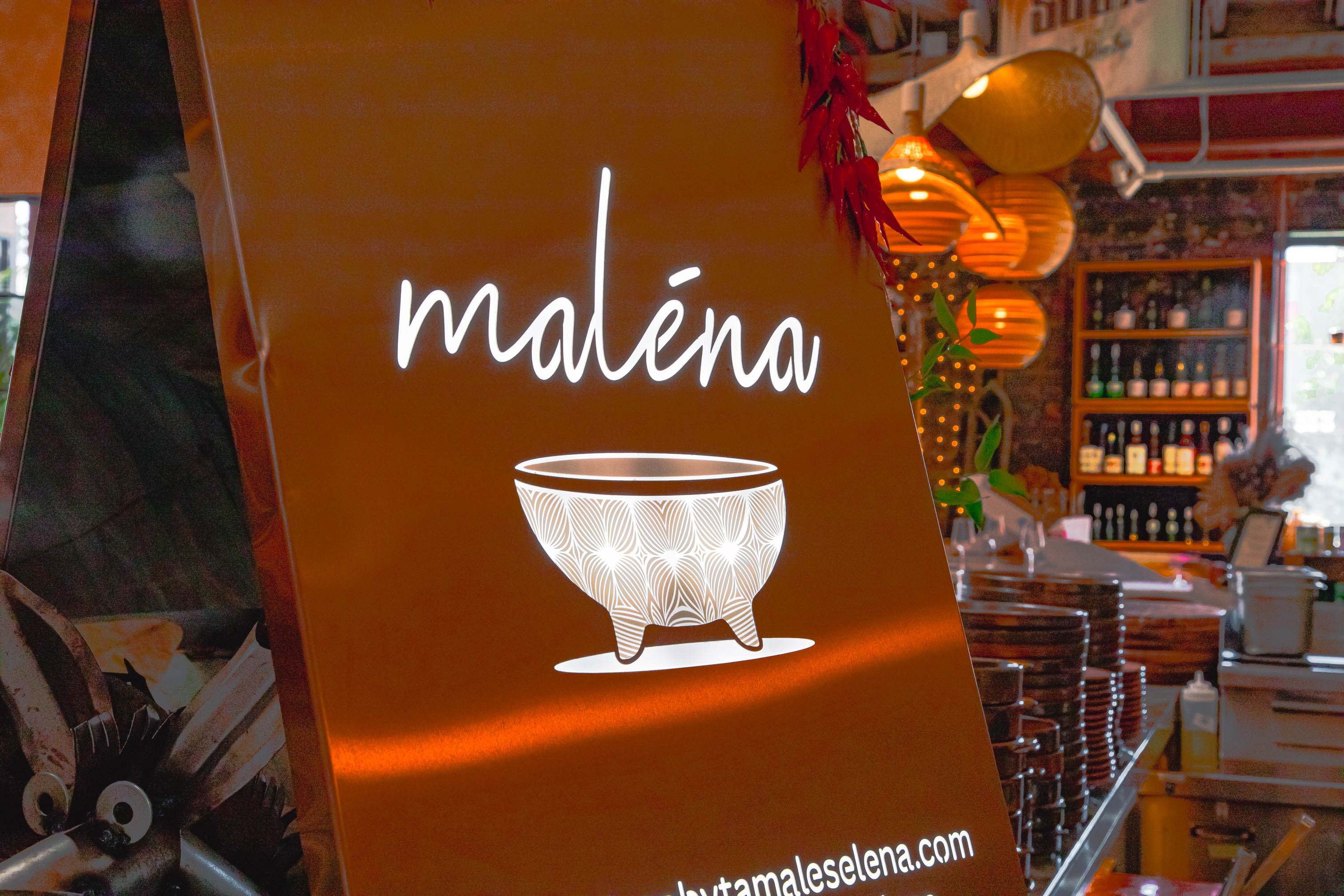 Illuminated restaurant sign on orange background with decorative bowl graphic