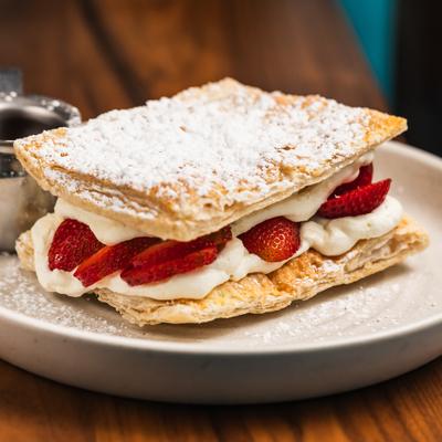 Strawberry Napoleon dusted with powdered sugar and served with syrup.