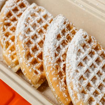 Waffles dusted with powdered sugar and served in a takeout container.