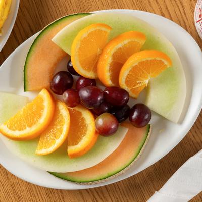 Fruit plate with cantaloupe, honeydew melon, oranges and black grapes.