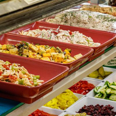 Salad and hot food bar featuring numereus trays with variety of foods.