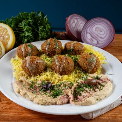 Falafel balls plated over rice with hummus.