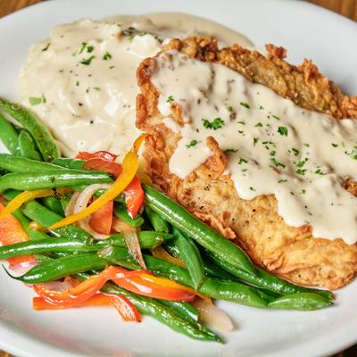 Chicken fried steak with gravy, mashed potatoes, and mixed vegetables.
