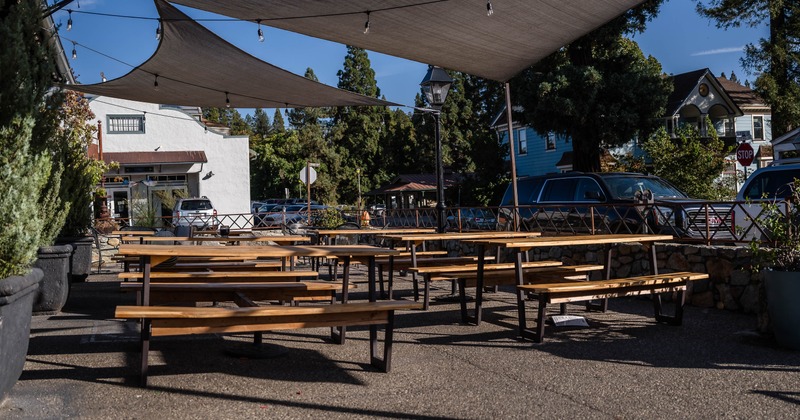 Outdoor seating area with picnic tables and shade sails