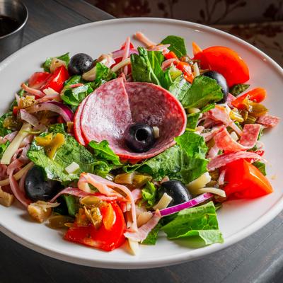 Salad with lettuce, salami, olives, and tomatoes.