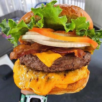 A large, stacked cheeseburger with various toppings.