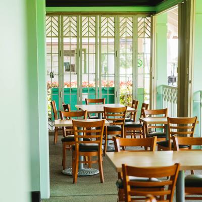 Bright dining area with tables and wooden chairs.