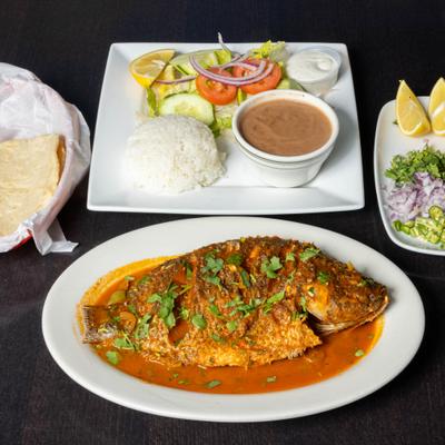 Fried whole fish served with salad, rice, and beans.