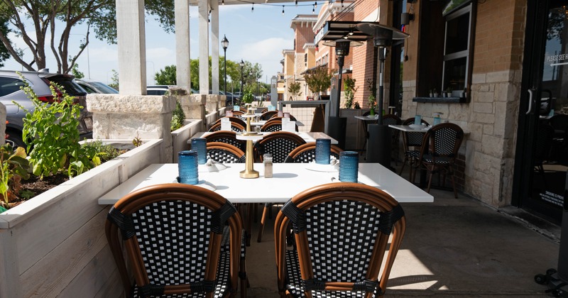 Outdoor restaurant seating with white tables, checkered chairs