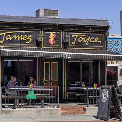 Storefront with signage and two tables under the awning.