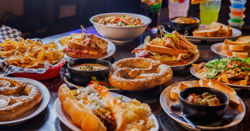 Table laden with various pub-style foods  and colorful drinks
