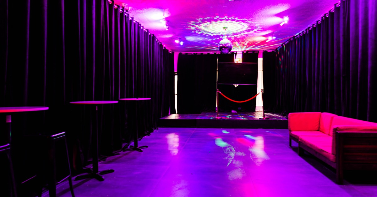 Interior, party room, dark space with violet purple lighting, sofa and high standing tables