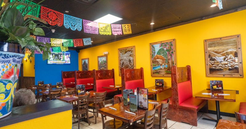 Interior of a colorful restaurant with red booths, wooden tables