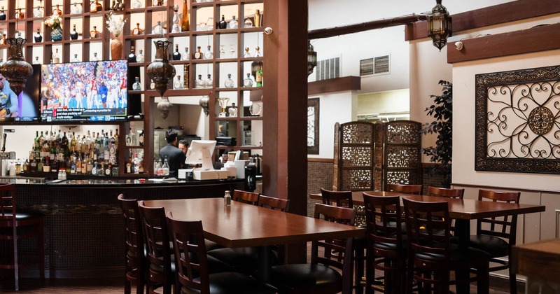 Interior of a bar with a starburst chandelier, wooden tables, and a stocked back bar