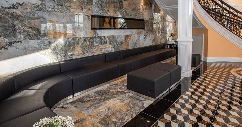 Luxurious modern interior with a dark gray sofa, marble walls and geometric tiled floor