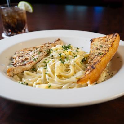 Fettuccine Alfredo with grilled chicken and bread.
