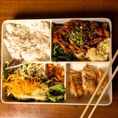Chicken Teriyaki Bento Box, with salad, dumplings, rice, kimchi, spinach, and potato salad.