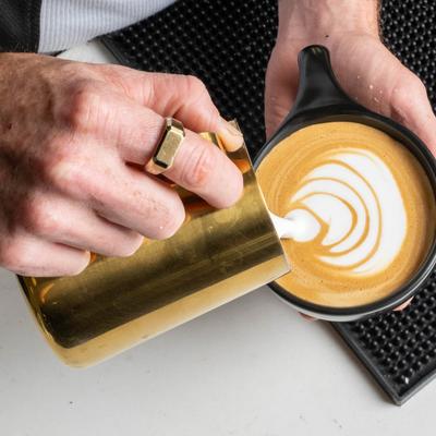 Hands serving a latte.