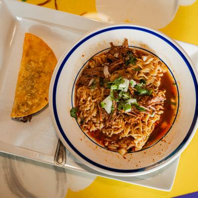 Birria ramen with noodles, beef broth, cilantro, onions, and a quesabirria taco.
