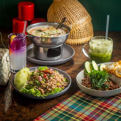 A vibrant spread of traditional Thai dishes, spicy salads, and colorful iced beverage.