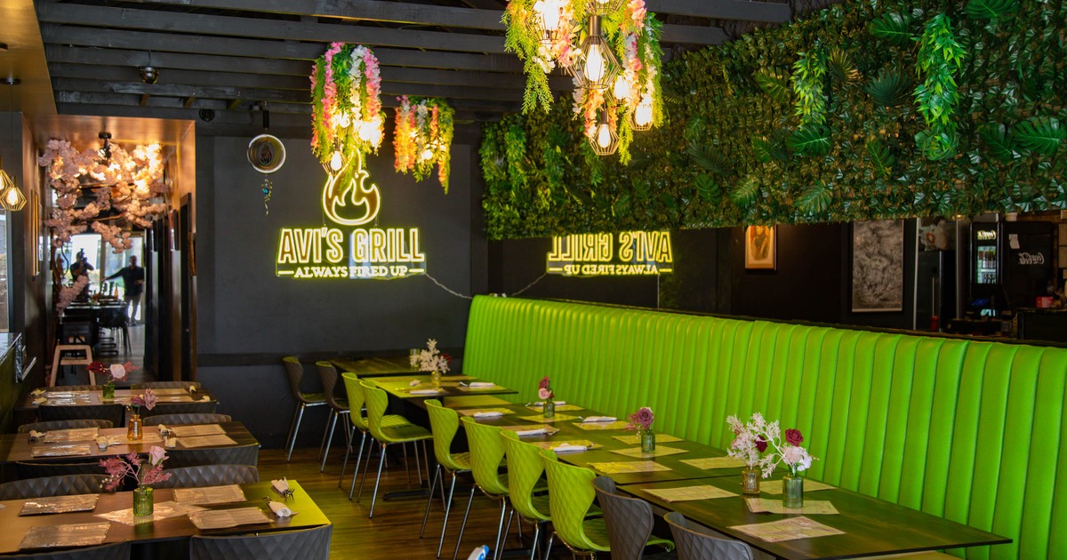 Interior of a modern restaurant with green booths and floral decor
