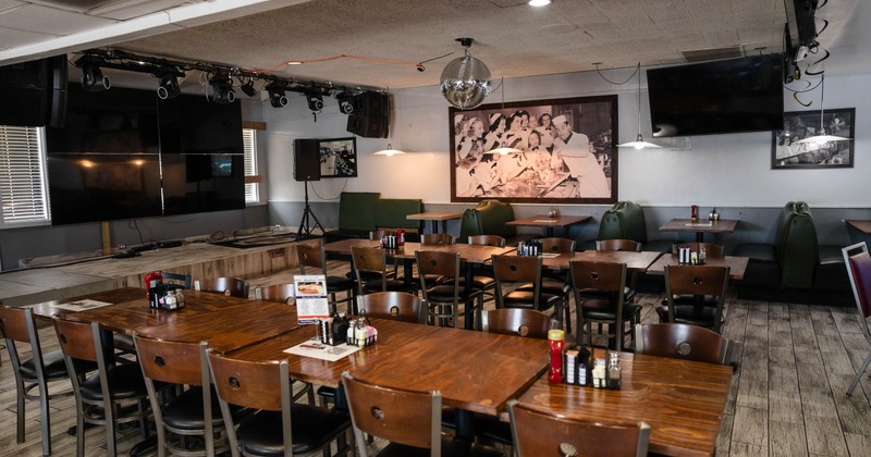 Interior, stage, wooden top table setups for twelve, large TV screens hanged on the walls
