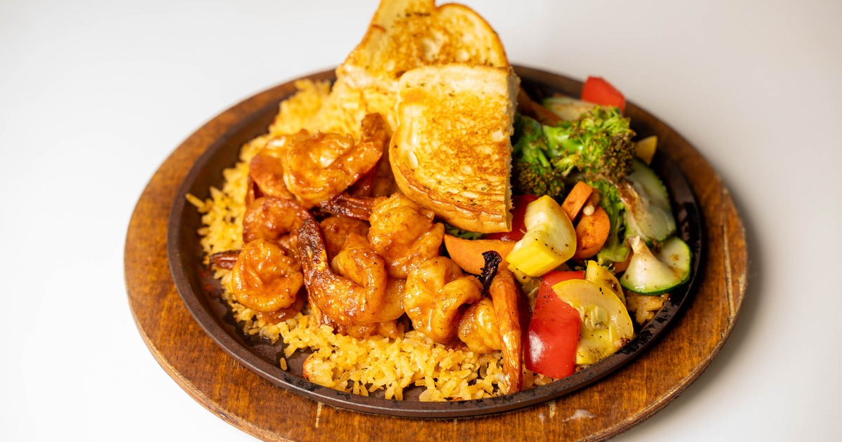 Marinated shrimp served over rice with mixed vegetables and toasted bread