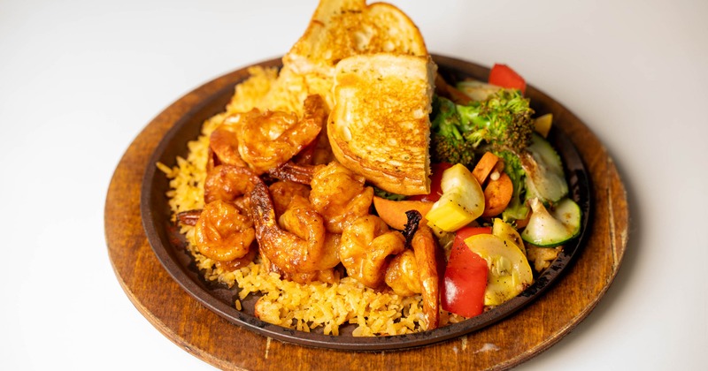 Marinated shrimp served over rice with mixed vegetables and toasted bread