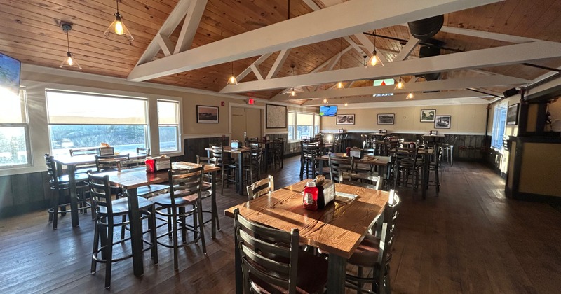 Bright interior with wooden tables, chairs, and large windows